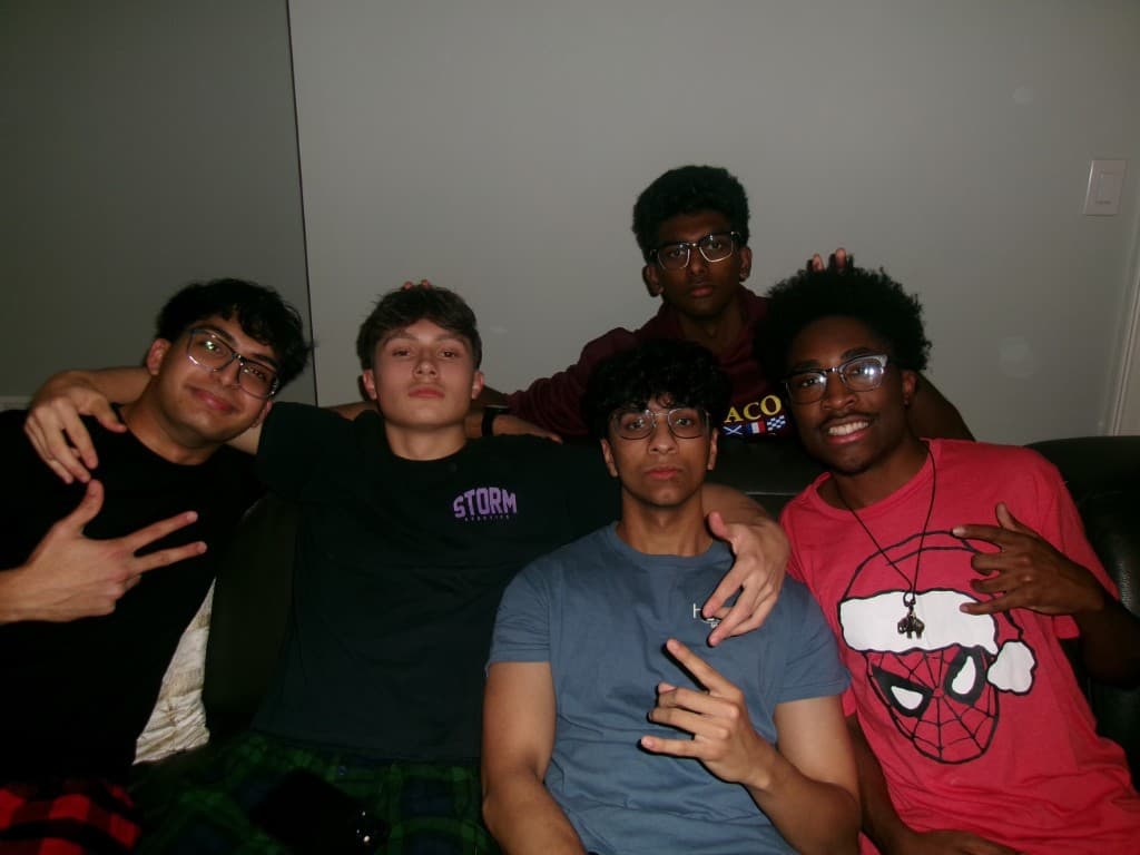Five friends sitting together on a couch indoors