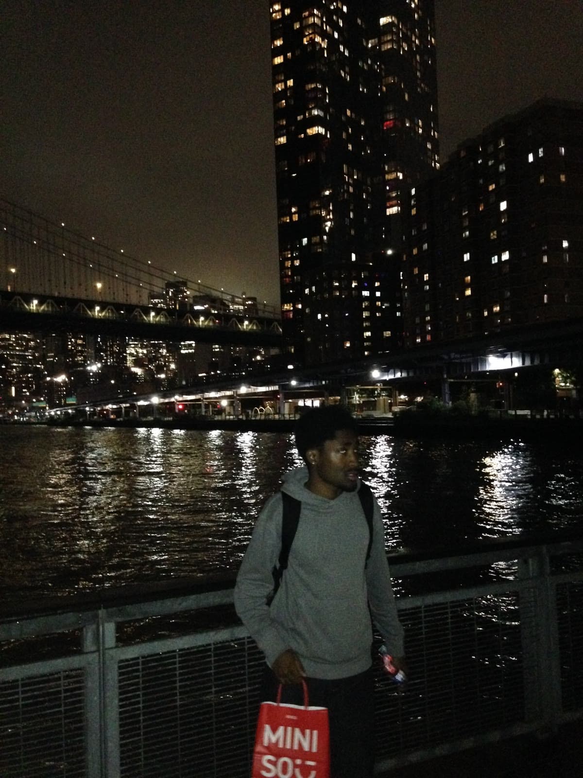 On the Brooklyn waterfront at night holding a Miniso bag
