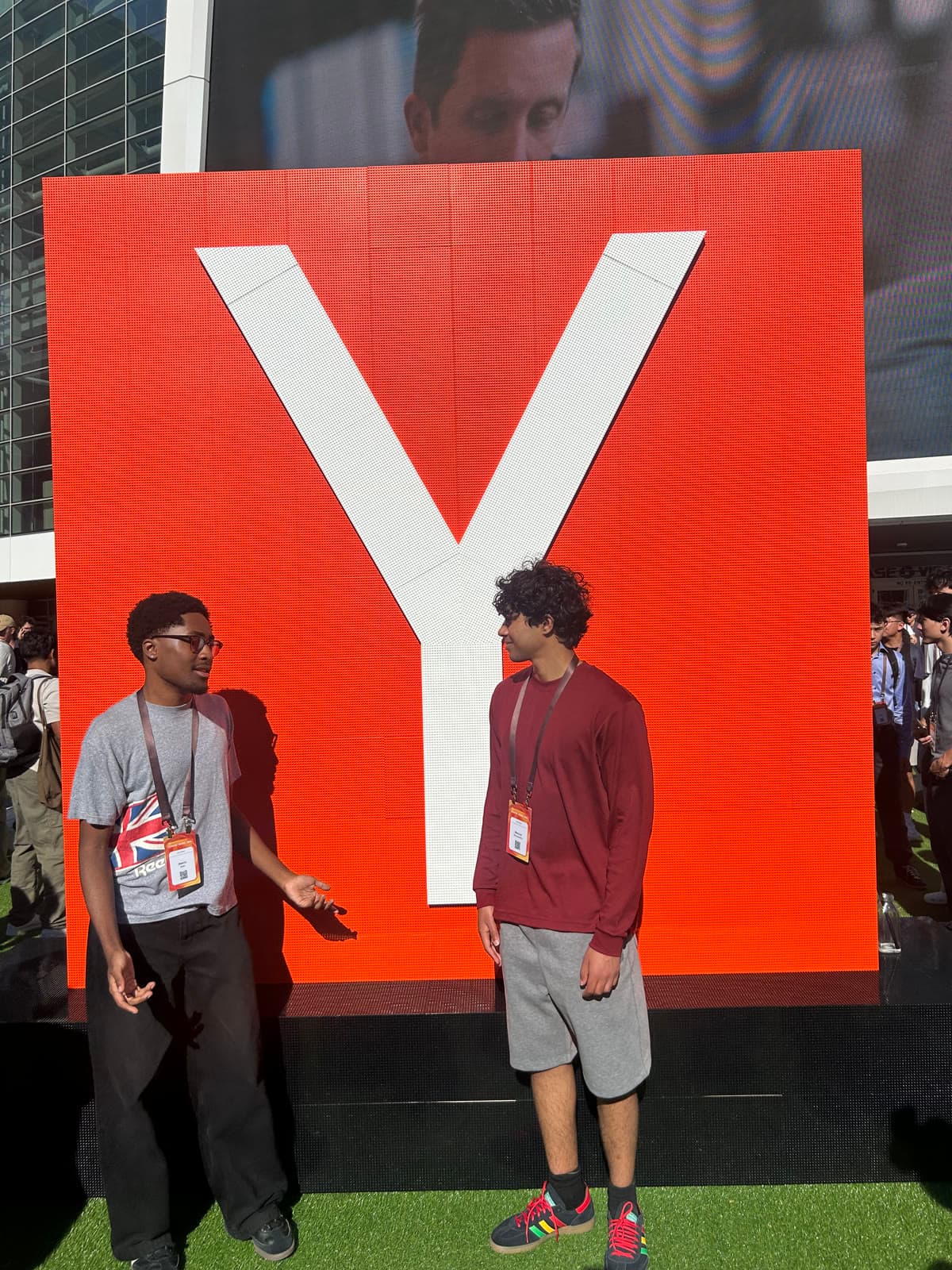 Two friends in front of a giant Y Combinator sign