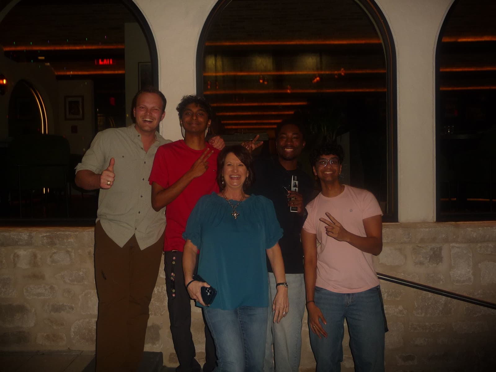 Five people smiling outside a restaurant at night