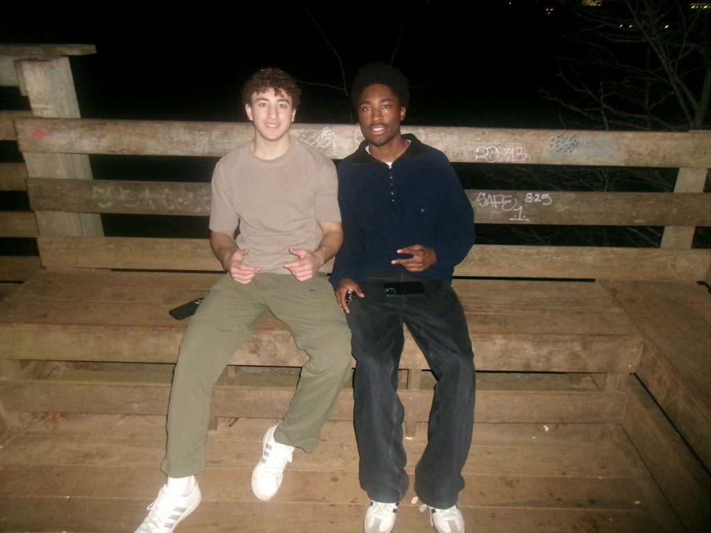 Two friends sitting on a wooden bench at night